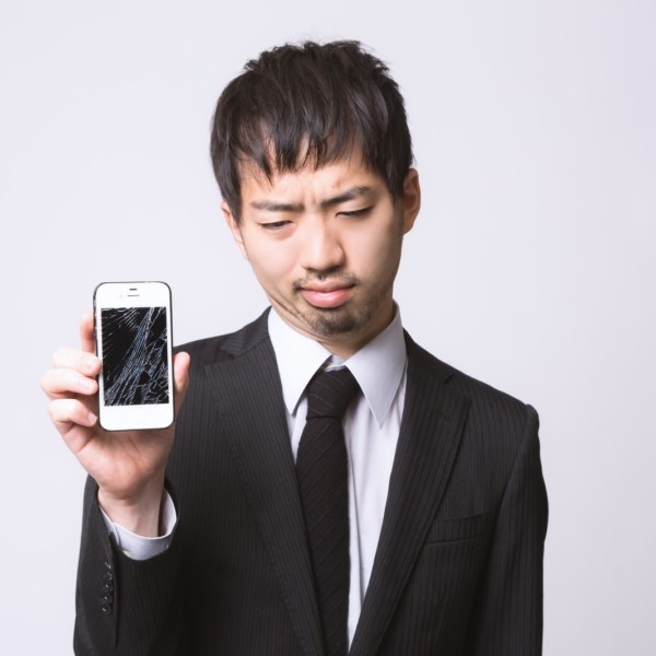 壊れたスマホを持つ男性